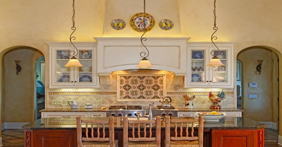 Example of a tuscan eat-in kitchen design in Santa Barbara with glass-front cabinets, white cabinets and an island