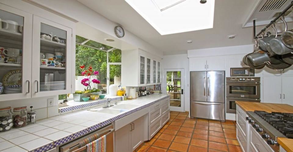 Bild på ett funkis kök och matrum, med en dubbel diskho, luckor med infälld panel, vita skåp, rostfria vitvaror, klinkergolv i terrakotta, en köksö och kaklad bänkskiva