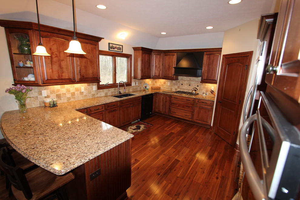 Inspiration for a mid-sized timeless u-shaped medium tone wood floor eat-in kitchen remodel in Cleveland with a double-bowl sink, raised-panel cabinets, medium tone wood cabinets, quartz countertops, beige backsplash, stainless steel appliances and an island
