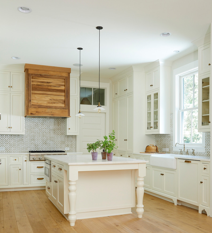 Idéer för ett klassiskt kök, med en rustik diskho, luckor med profilerade fronter, vita skåp, marmorbänkskiva, stänkskydd i keramik, rostfria vitvaror, ljust trägolv och en köksö