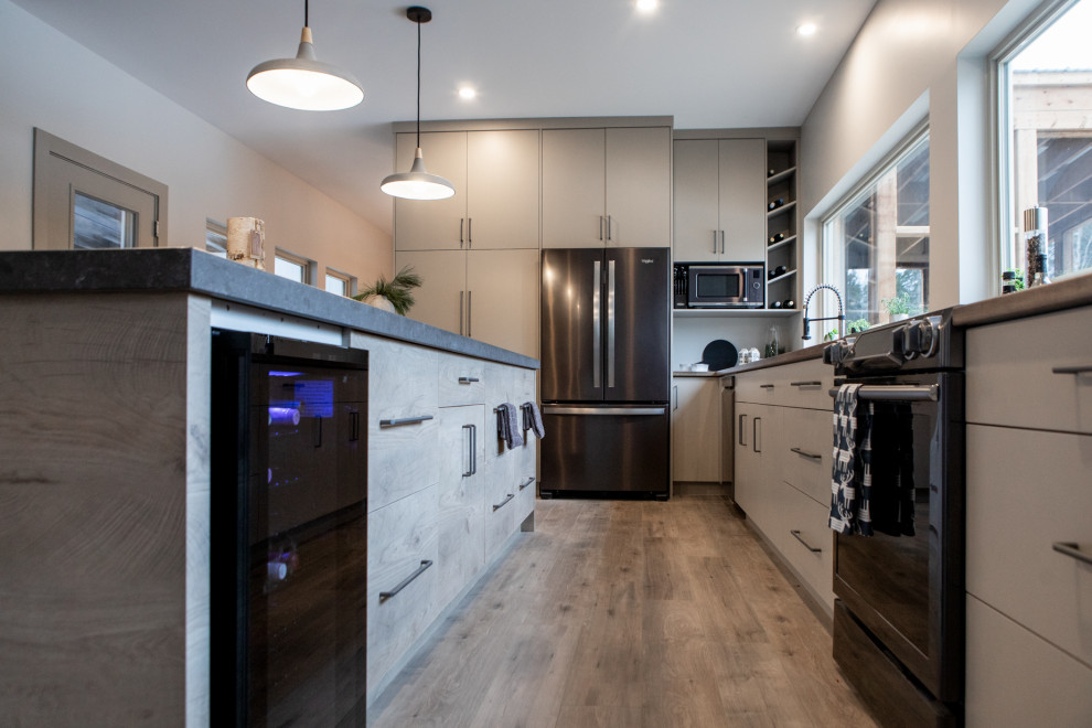 Foto di una grande cucina moderna chiusa con lavello a doppia vasca, ante lisce, top in laminato, elettrodomestici neri e pavimento in laminato