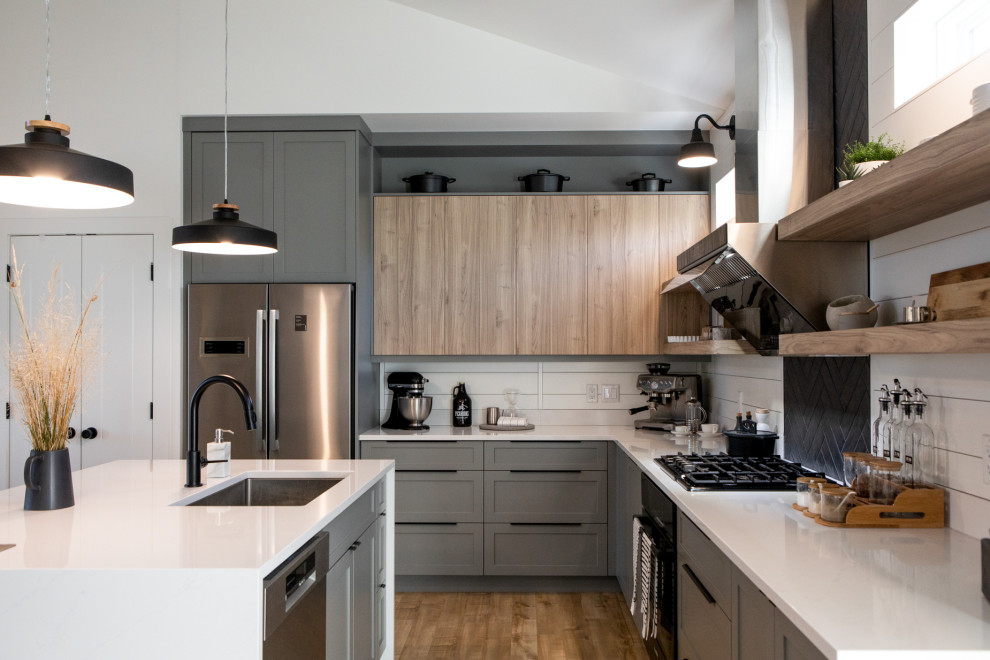 Open concept kitchen - mid-sized scandinavian l-shaped laminate floor open concept kitchen idea in Other with an undermount sink, shaker cabinets, gray cabinets, solid surface countertops, black backsplash, ceramic backsplash, stainless steel appliances, an island and white countertops