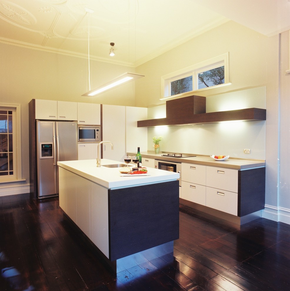 Imagen de cocina actual con electrodomésticos de acero inoxidable, armarios con paneles lisos y puertas de armario blancas