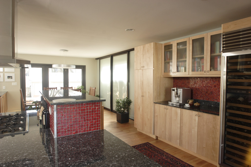 Ejemplo de cocina moderna grande con armarios con paneles lisos, puertas de armario de madera clara, salpicadero rojo, electrodomésticos de acero inoxidable, suelo de madera clara y una isla