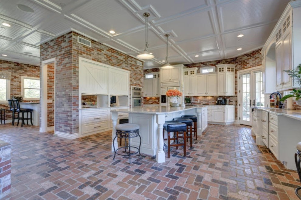 Inspiration for a large farmhouse u-shaped brick floor open concept kitchen remodel in Phoenix with a farmhouse sink, white cabinets, white appliances and an island