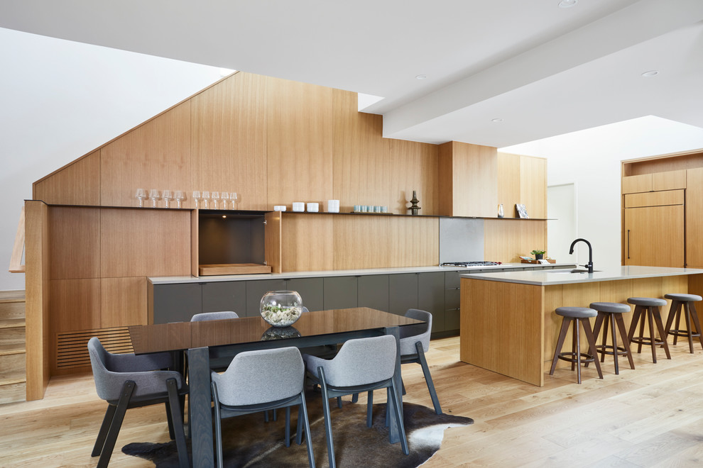 Contemporary kitchen/diner in Austin with a single-bowl sink, flat-panel cabinets, grey cabinets, wood splashback, integrated appliances, light hardwood flooring, an island and beige floors.
