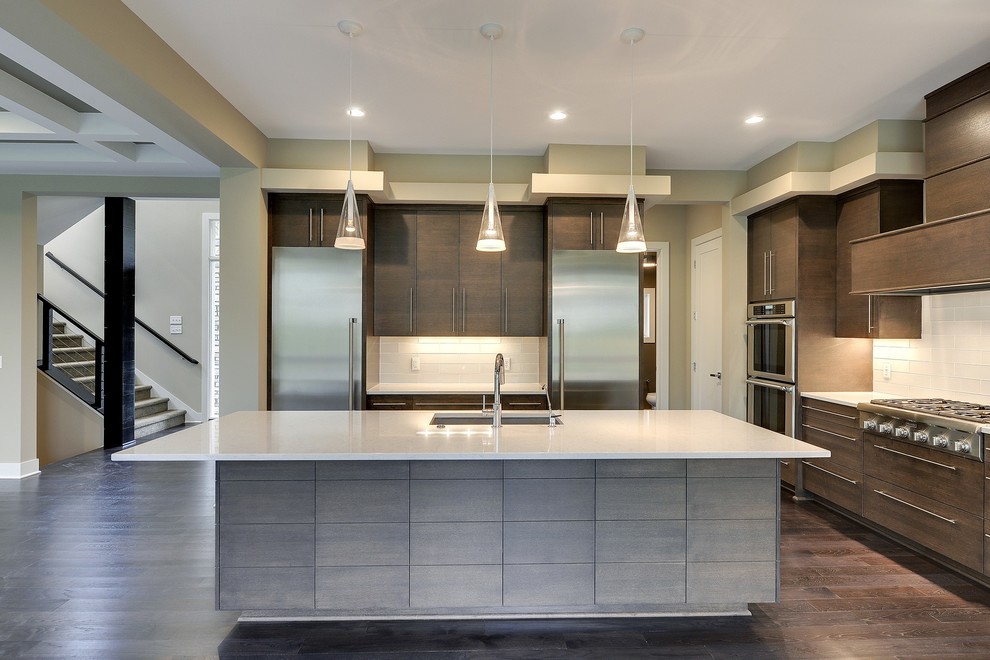 Large traditional single-wall kitchen/diner in Minneapolis with a submerged sink, flat-panel cabinets, dark wood cabinets, marble worktops, white splashback, porcelain splashback, stainless steel appliances, dark hardwood flooring and an island.