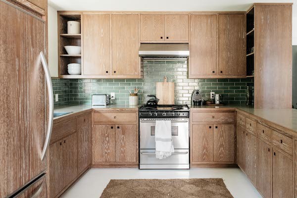 Design ideas for a small world-inspired u-shaped enclosed kitchen in Los Angeles with a built-in sink, flat-panel cabinets, medium wood cabinets, laminate countertops, green splashback, metro tiled splashback, integrated appliances, concrete flooring, no island and white floors.
