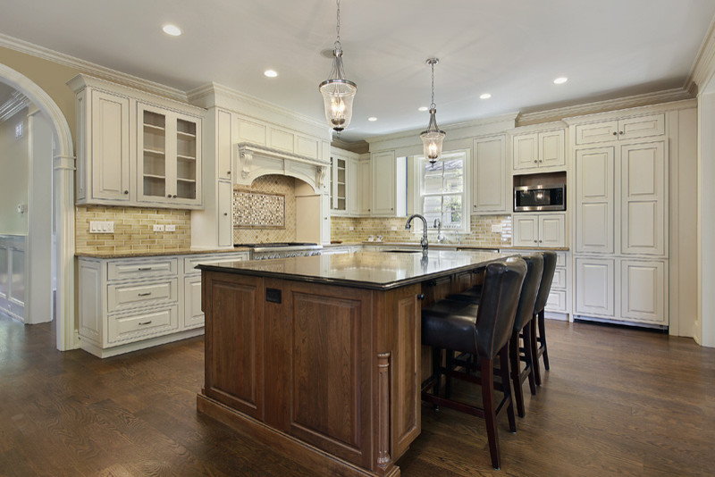 Mid-sized trendy u-shaped dark wood floor eat-in kitchen photo in Chicago with a double-bowl sink, raised-panel cabinets, white cabinets, soapstone countertops, beige backsplash, stone tile backsplash, stainless steel appliances and an island