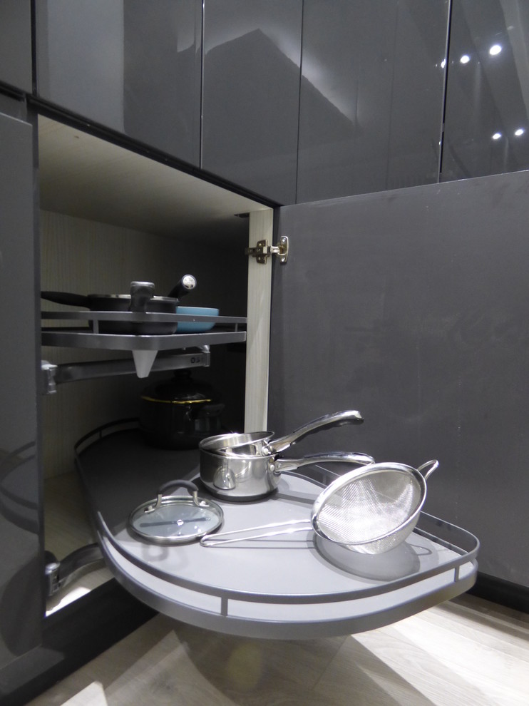 Foto di una grande cucina minimal con lavello integrato, ante lisce, ante grigie, top in superficie solida, elettrodomestici neri e pavimento grigio