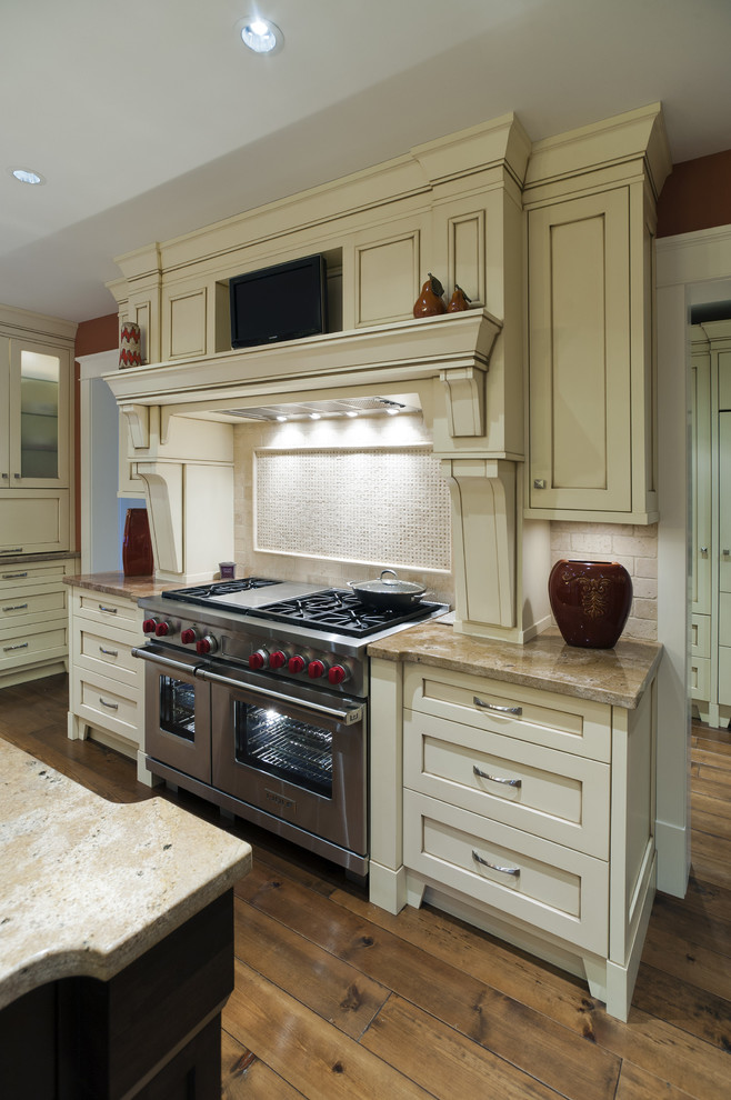 Klassisk inredning av ett kök, med en undermonterad diskho, släta luckor, beige skåp och granitbänkskiva