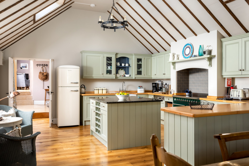 Design ideas for a large rural u-shaped open plan kitchen in Gloucestershire with recessed-panel cabinets, green cabinets, wood worktops, medium hardwood flooring, an island, brown floors and brown worktops.