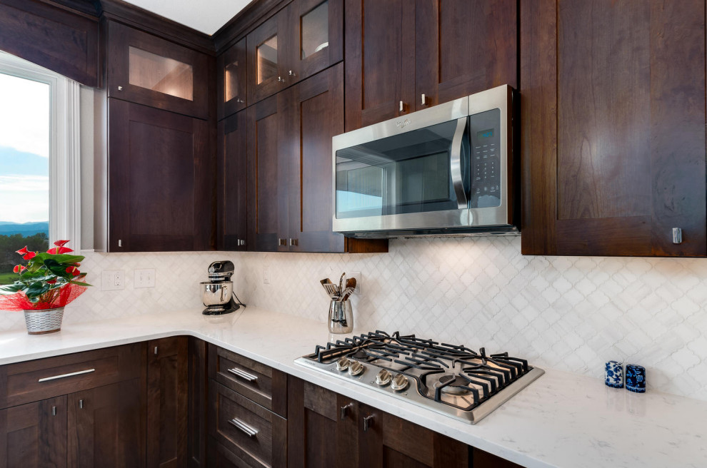 Exempel på ett mellanstort klassiskt vit vitt kök, med en dubbel diskho, skåp i shakerstil, bruna skåp, bänkskiva i kvarts, vitt stänkskydd, stänkskydd i marmor, rostfria vitvaror, mörkt trägolv, en köksö och brunt golv
