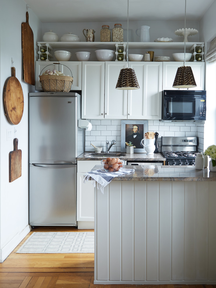 Klassisk inredning av ett avskilt, litet l-kök, med en dubbel diskho, skåp i shakerstil, vita skåp, granitbänkskiva, vitt stänkskydd, stänkskydd i tunnelbanekakel, rostfria vitvaror, mellanmörkt trägolv och en halv köksö