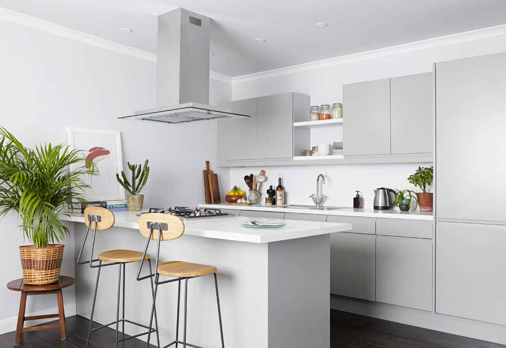 Design ideas for a contemporary kitchen in London with flat-panel cabinets, grey cabinets, white splashback, dark hardwood flooring, an island, laminate countertops, ceramic splashback and white worktops.
