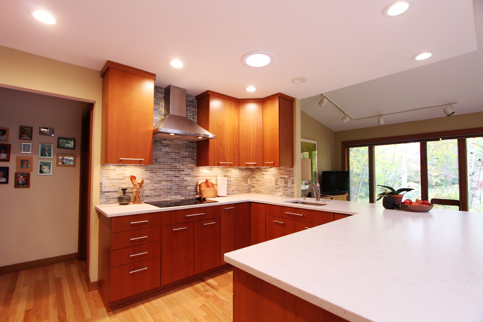 Inredning av ett modernt litet kök, med en undermonterad diskho, släta luckor, skåp i mellenmörkt trä, bänkskiva i kvarts, flerfärgad stänkskydd, stänkskydd i glaskakel, rostfria vitvaror, ljust trägolv och en halv köksö