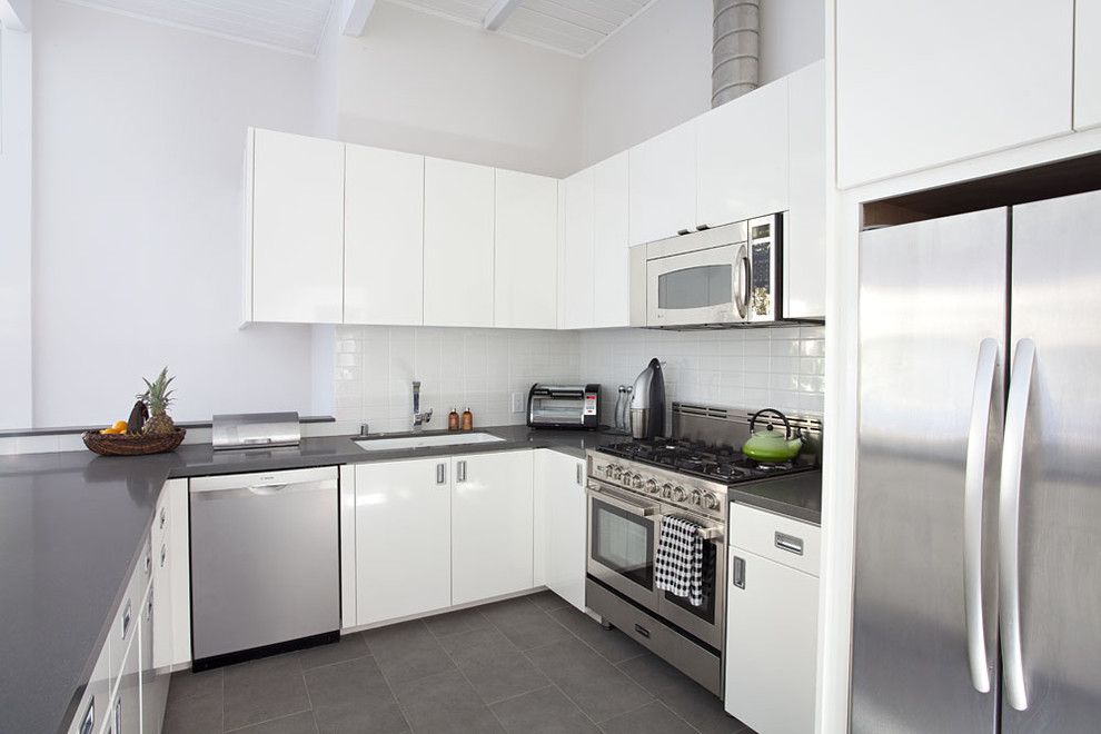 Immagine di una cucina ad U moderna con elettrodomestici in acciaio inossidabile, top in quarzo composito e pavimento grigio