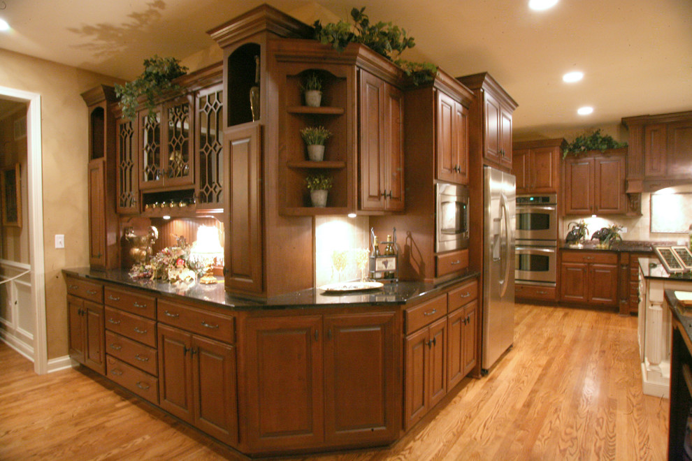 Exempel på ett stort klassiskt kök, med luckor med upphöjd panel, skåp i mellenmörkt trä, granitbänkskiva, beige stänkskydd, stänkskydd i keramik, rostfria vitvaror, mellanmörkt trägolv och flera köksöar
