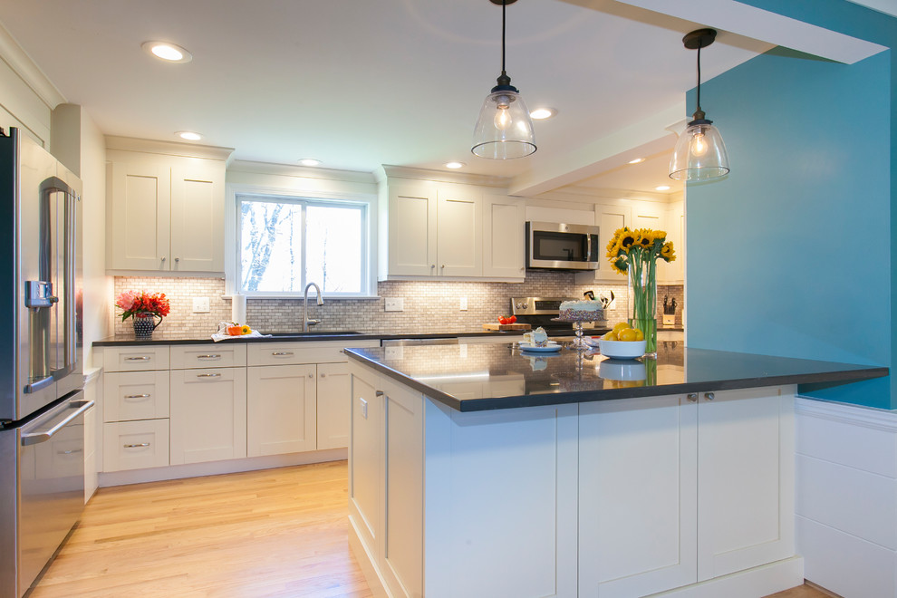 Mid-sized trendy l-shaped light wood floor and yellow floor eat-in kitchen photo in Bridgeport with a single-bowl sink, recessed-panel cabinets, white cabinets, quartzite countertops, beige backsplash, limestone backsplash, stainless steel appliances, a peninsula and black countertops
