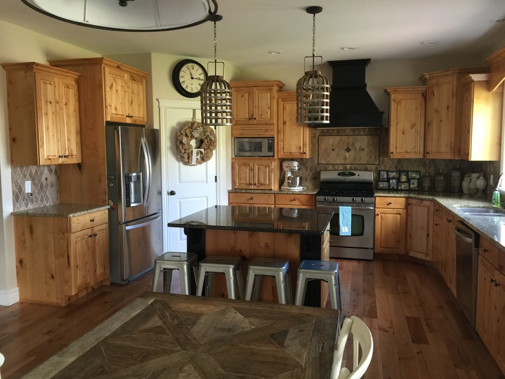 Example of a mid-sized mountain style u-shaped dark wood floor and brown floor eat-in kitchen design in Austin with a drop-in sink, raised-panel cabinets, medium tone wood cabinets, granite countertops, brown backsplash, ceramic backsplash, stainless steel appliances and an island