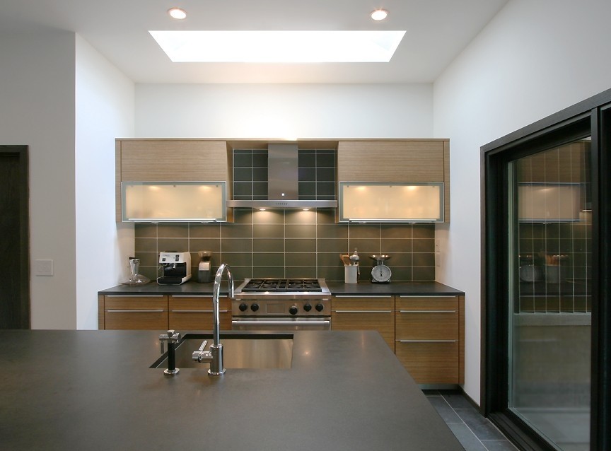 Bild på ett mellanstort kök, med en undermonterad diskho, släta luckor, skåp i mellenmörkt trä, marmorbänkskiva, grått stänkskydd, stänkskydd i glaskakel, integrerade vitvaror, skiffergolv och en köksö