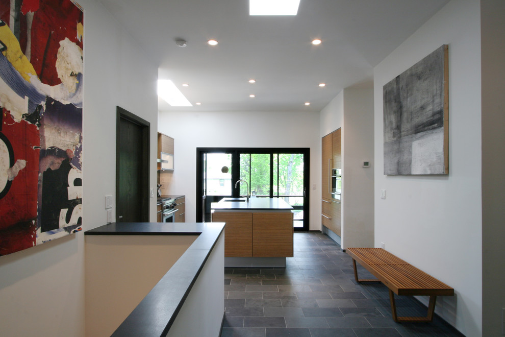 Photo of a medium sized contemporary galley kitchen in Minneapolis with flat-panel cabinets, medium wood cabinets, integrated appliances, a submerged sink, marble worktops, grey splashback, glass tiled splashback, slate flooring and an island.