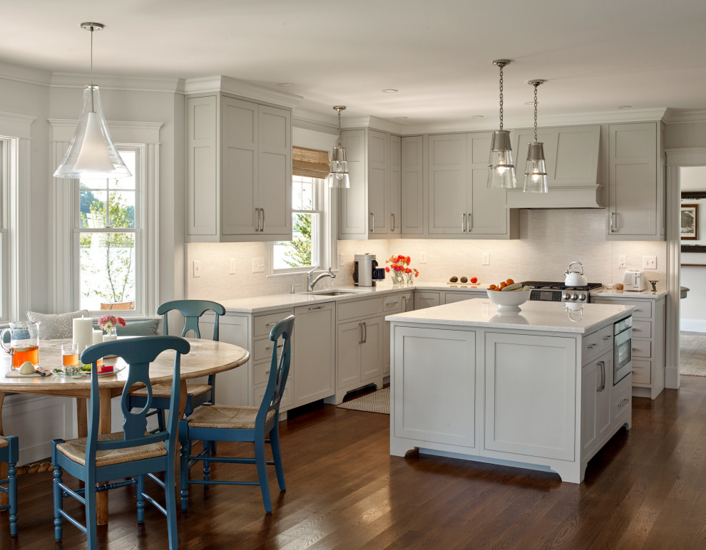 Foto di una cucina costiera con lavello sottopiano, ante in stile shaker, ante grigie, elettrodomestici in acciaio inossidabile, parquet scuro, pavimento marrone e top bianco