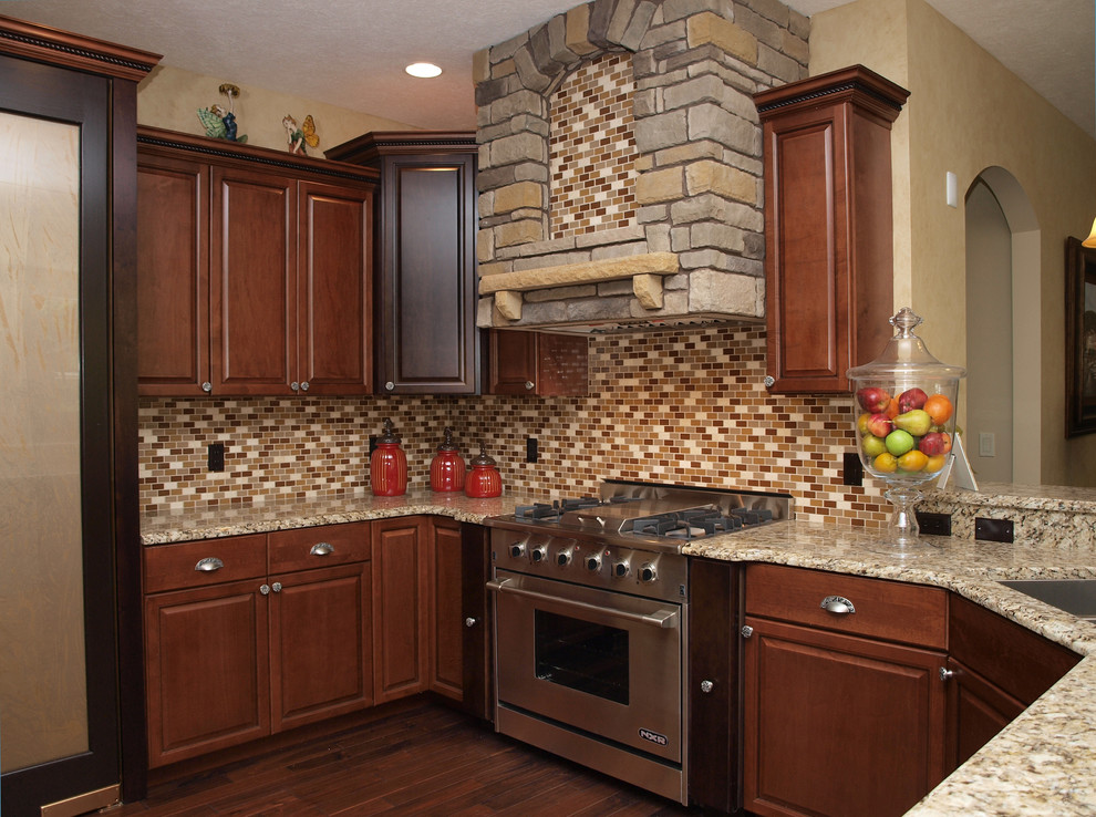 Exempel på ett mellanstort klassiskt kök, med en undermonterad diskho, luckor med profilerade fronter, skåp i mellenmörkt trä, granitbänkskiva, orange stänkskydd, stänkskydd i glaskakel, rostfria vitvaror och mellanmörkt trägolv