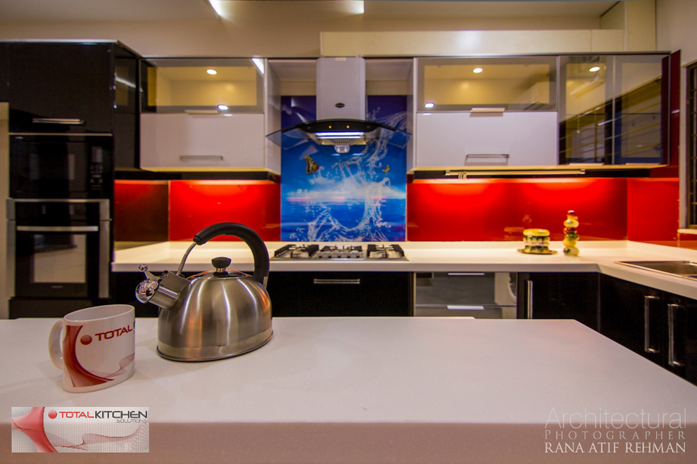 Foto di una cucina design chiusa e di medie dimensioni con lavello a doppia vasca, ante nere, top in laminato, paraspruzzi rosso, paraspruzzi con piastrelle di vetro, elettrodomestici neri e pavimento con piastrelle in ceramica