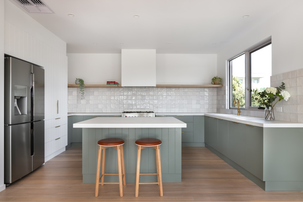Idee per una cucina design con ante lisce, ante verdi, paraspruzzi bianco, elettrodomestici in acciaio inossidabile, pavimento in legno massello medio, pavimento marrone e top bianco