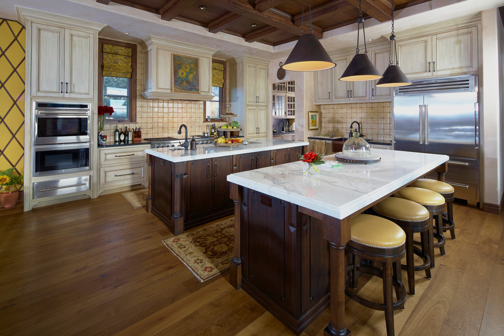 Klassisk inredning av ett kök, med luckor med infälld panel, skåp i ljust trä, beige stänkskydd och rostfria vitvaror