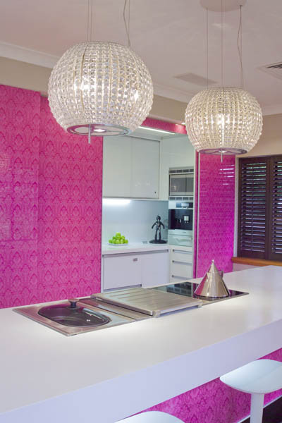 Imagen de cocina moderna grande con armarios con paneles lisos, encimera de cuarzo compacto, salpicadero rosa, salpicadero de vidrio templado, electrodomésticos de acero inoxidable, suelo de madera clara y una isla