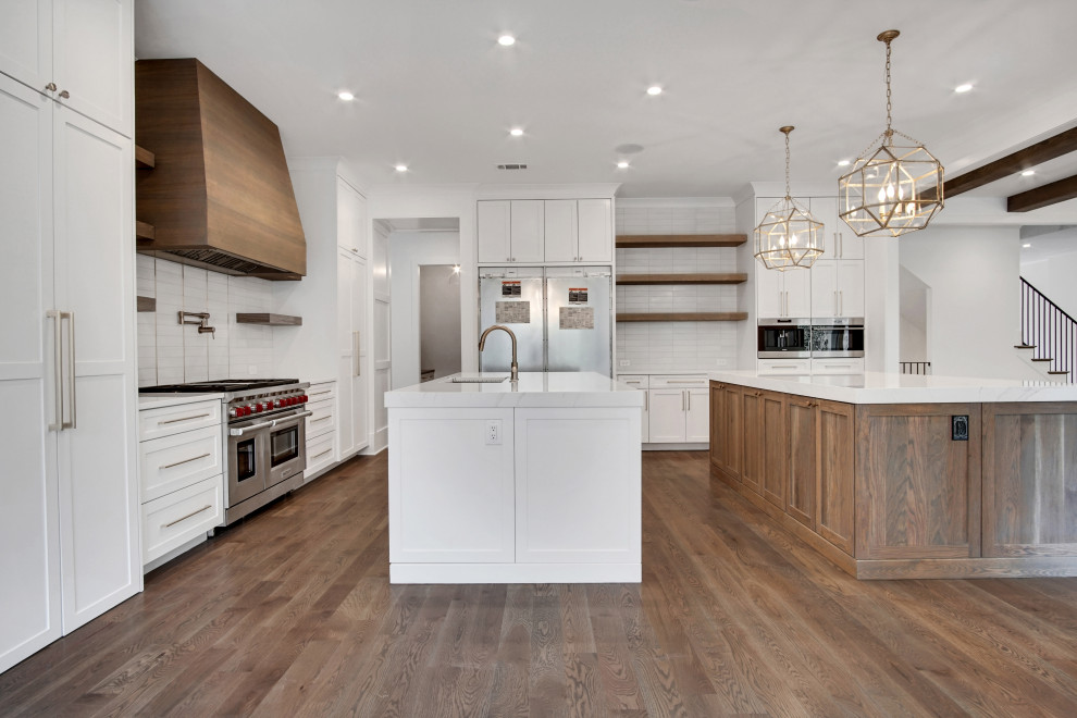 Eat-in kitchen - huge transitional l-shaped medium tone wood floor and gray floor eat-in kitchen idea in Atlanta with a single-bowl sink, shaker cabinets, white cabinets, quartzite countertops, white backsplash, porcelain backsplash, paneled appliances, two islands and white countertops