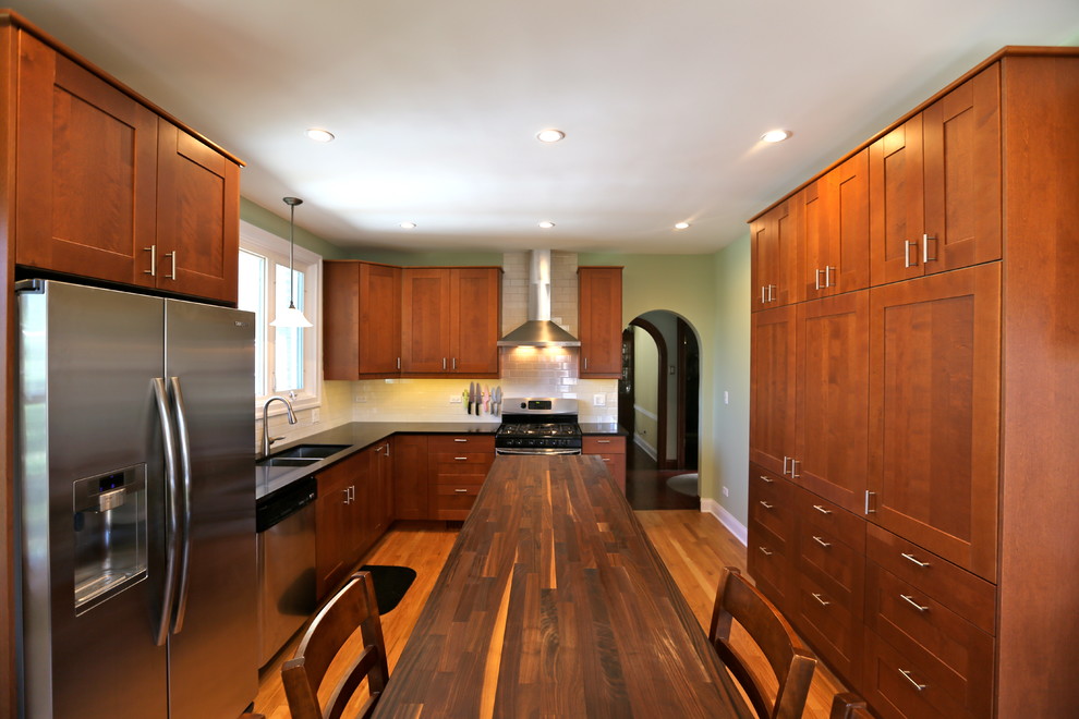 Foto på ett stort funkis kök och matrum, med en dubbel diskho, skåp i shakerstil, skåp i mellenmörkt trä, bänkskiva i kvarts, vitt stänkskydd, stänkskydd i keramik, rostfria vitvaror, ljust trägolv och en köksö