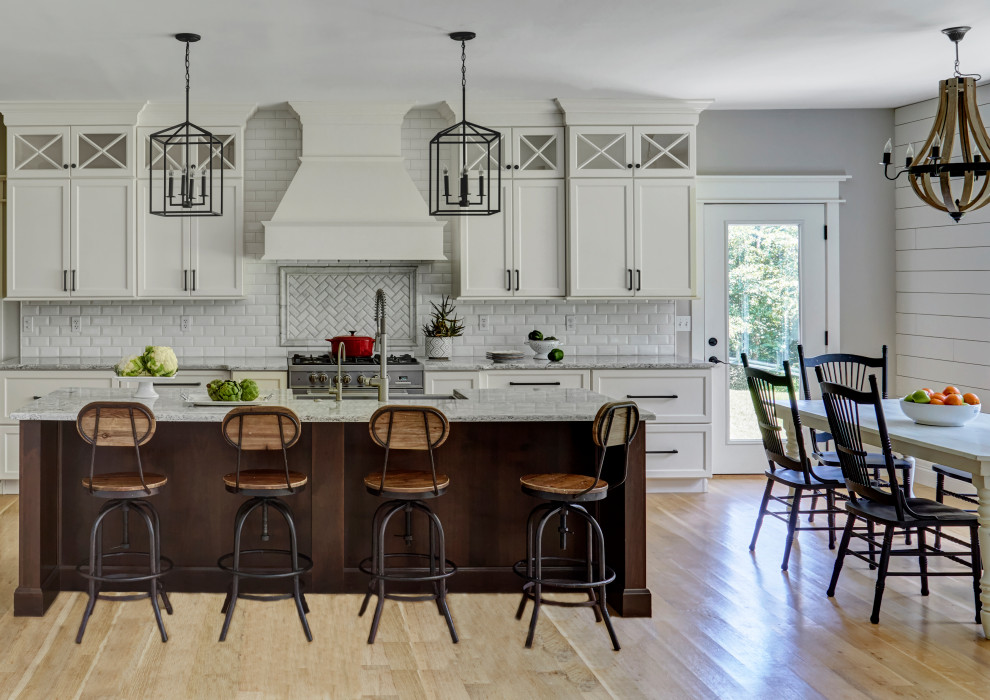 Eat-in kitchen - country galley light wood floor and beige floor eat-in kitchen idea in Huntington with a farmhouse sink, recessed-panel cabinets, white cabinets, white backsplash, subway tile backsplash, stainless steel appliances, an island and gray countertops