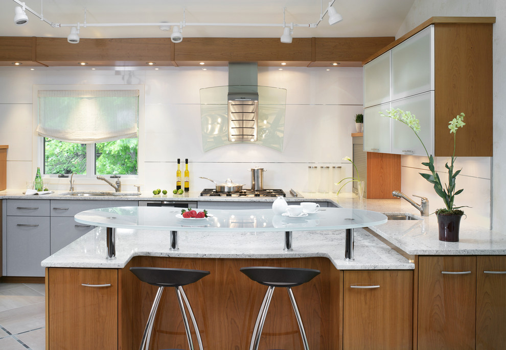 ニューヨークにあるコンテンポラリースタイルのおしゃれなキッチン (アンダーカウンターシンク、フラットパネル扉のキャビネット、中間色木目調キャビネット、ガラスカウンター、白いキッチンパネル、シルバーの調理設備) の写真