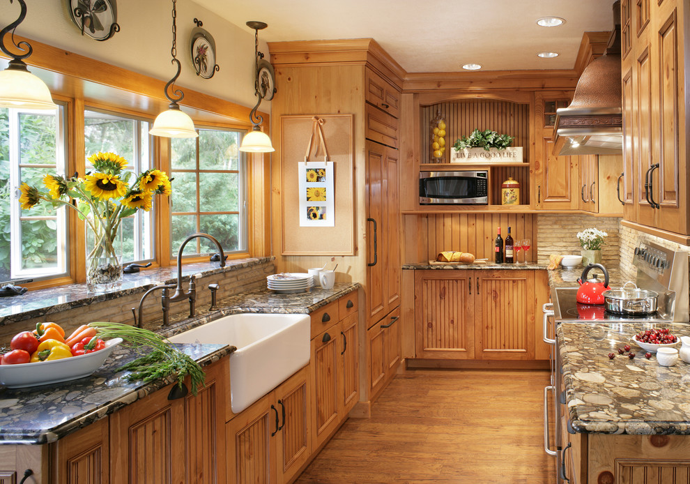 Elegant u-shaped enclosed kitchen photo in New York with a farmhouse sink, medium tone wood cabinets, granite countertops, beige backsplash and paneled appliances