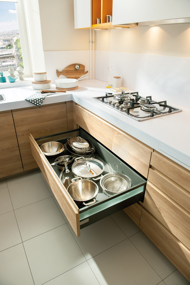 Kleine Moderne Küche in L-Form mit Waschbecken, Küchenrückwand in Weiß, Glasrückwand, Küchengeräten aus Edelstahl, Keramikboden und hellen Holzschränken in London