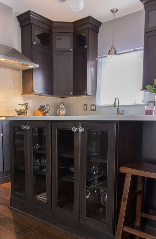 Medium sized classic l-shaped kitchen in Detroit with a submerged sink, shaker cabinets, dark wood cabinets, engineered stone countertops, grey splashback, metro tiled splashback, stainless steel appliances, dark hardwood flooring, an island and brown floors.
