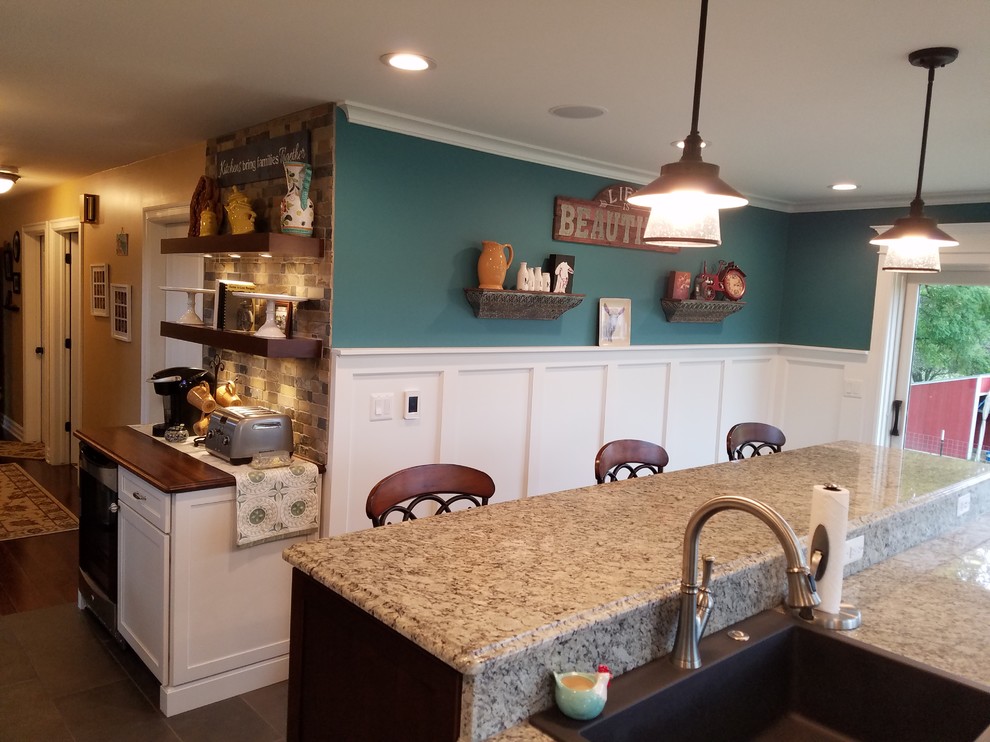 Klassisk inredning av ett stort kök, med en nedsänkt diskho, skåp i shakerstil, vita skåp, granitbänkskiva, stänkskydd i keramik, rostfria vitvaror, klinkergolv i porslin, en köksö och grått golv