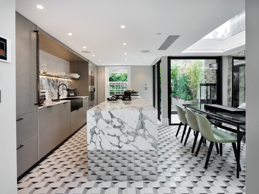 Photo of a large contemporary galley kitchen/diner in London with a belfast sink, flat-panel cabinets, grey cabinets, grey splashback, stainless steel appliances, an island, multi-coloured floors and grey worktops.