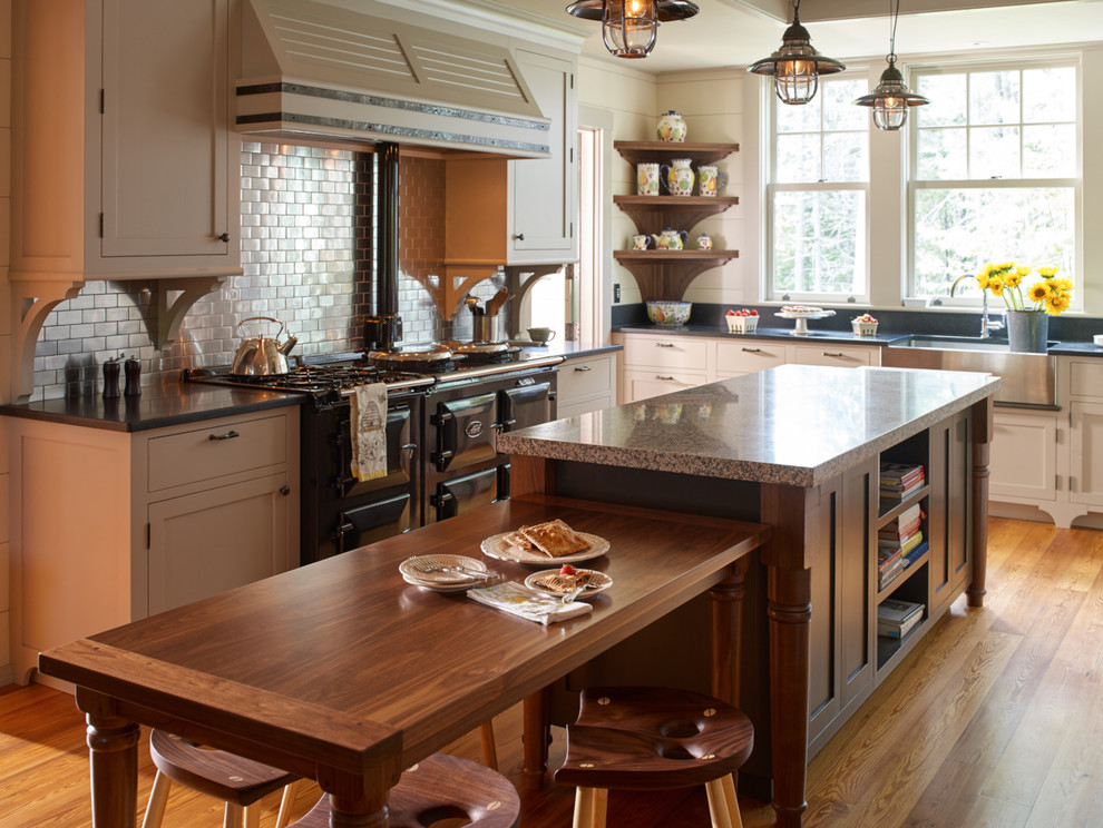 Urige Wohnküche mit Landhausspüle, Schrankfronten im Shaker-Stil, Rückwand aus Metrofliesen, schwarzen Elektrogeräten, braunem Holzboden und Kücheninsel in Portland Maine