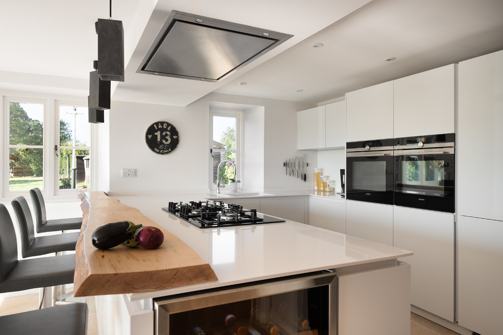 Foto di una cucina design di medie dimensioni con ante lisce, ante bianche, top in quarzite, paraspruzzi bianco, elettrodomestici neri, pavimento in gres porcellanato, pavimento beige e top bianco