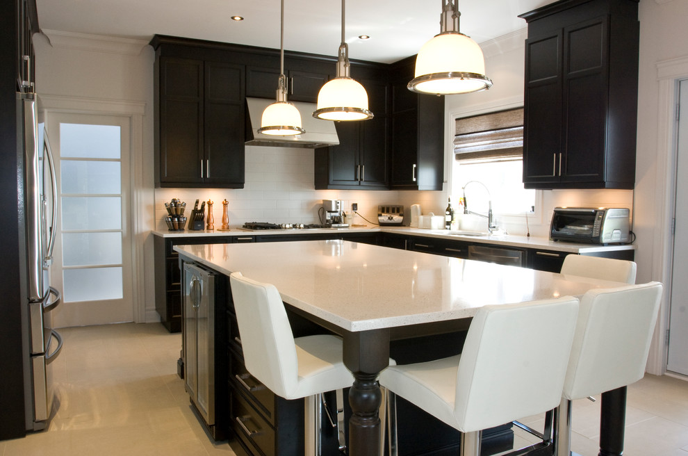 This is an example of a medium sized contemporary u-shaped kitchen/diner in Montreal with shaker cabinets, dark wood cabinets, white splashback, metro tiled splashback, stainless steel appliances, light hardwood flooring and an island.