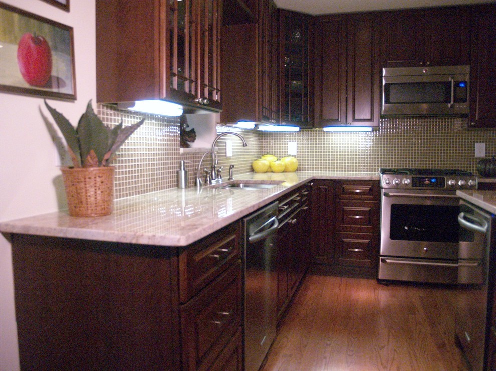 Idéer för att renovera ett mellanstort vintage kök, med en nedsänkt diskho, luckor med upphöjd panel, skåp i mörkt trä, granitbänkskiva, grönt stänkskydd, glaspanel som stänkskydd, rostfria vitvaror, mellanmörkt trägolv och en köksö