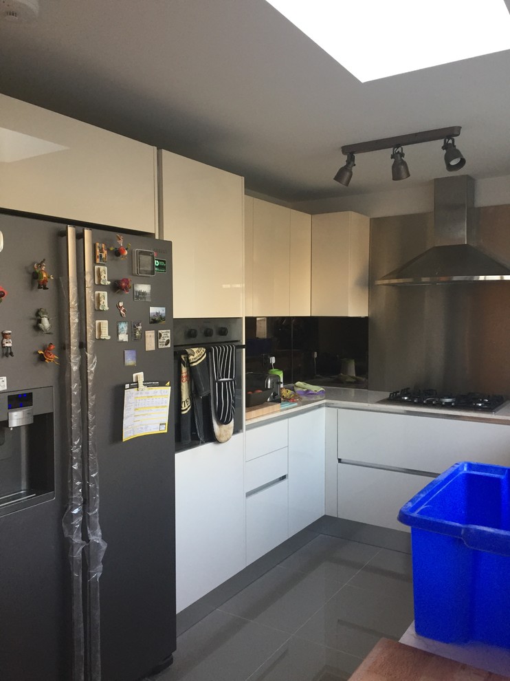 Modern u-shaped kitchen in London with a built-in sink, flat-panel cabinets, beige cabinets, composite countertops, brown splashback, ceramic splashback and ceramic flooring.