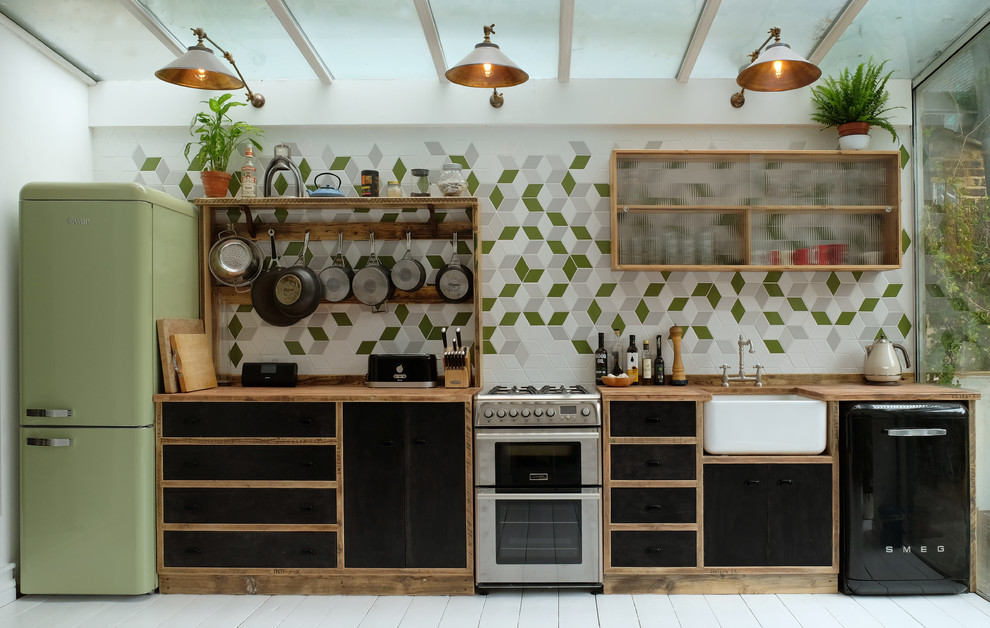Inspiration for a scandi single-wall enclosed kitchen in London with a belfast sink, flat-panel cabinets, black cabinets, wood worktops, multi-coloured splashback, coloured appliances, painted wood flooring, no island and ceramic splashback.