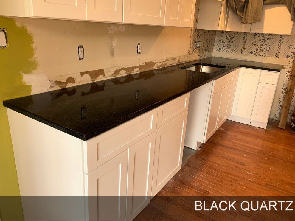 Medium sized modern single-wall kitchen/diner in Atlanta with a built-in sink, quartz worktops, black splashback, black appliances, black worktops, recessed-panel cabinets, white cabinets, plywood flooring, an island and brown floors.