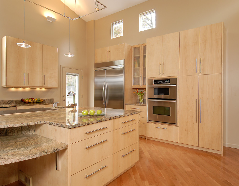 Modelo de cocina contemporánea con electrodomésticos de acero inoxidable, armarios con paneles lisos y puertas de armario de madera clara