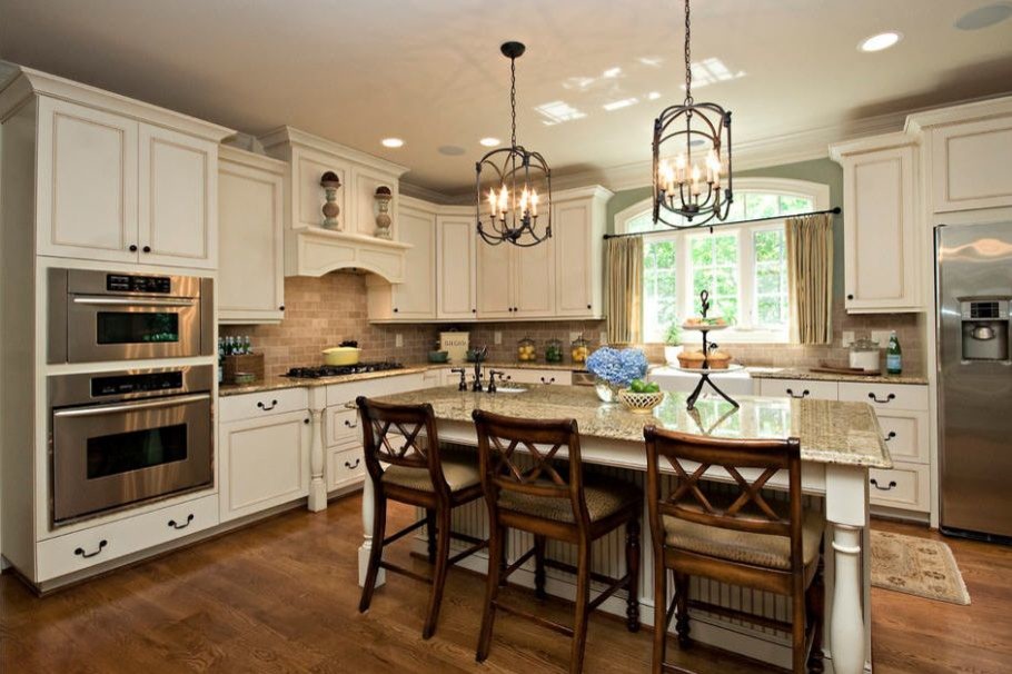 Kitchen - large traditional dark wood floor and brown floor kitchen idea in DC Metro with a farmhouse sink, recessed-panel cabinets, white cabinets, granite countertops, brown backsplash, stone tile backsplash, stainless steel appliances, an island and multicolored countertops